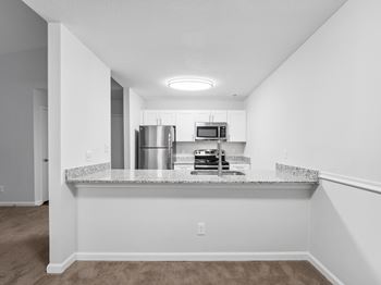 A kitchen with white cabinets and a granite countertop.